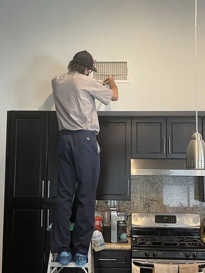 Technician inspecting an air vent during HVAC service in Dumas